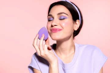 Happy modern  girl hold lilac makeup egg sponge enjoy perfect trendy lavender make up, closed eyes....