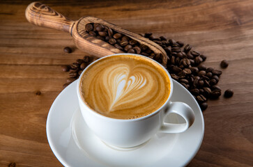 Roasted coffee beans with cappuccino with heartbeat foam pattern
