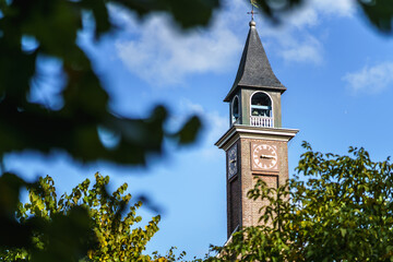Small church steeple with clock and time dial in a small Dutch village