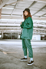 Portrait, fashion or stylish young gen z woman stand in a warehouse with green clothing. Trendy,...