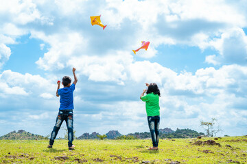 Back view shot of teenager kids flying kite on top of mountain - concept of weekend holidays, relaxation and playful childhood lifestyles. - Powered by Adobe