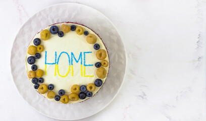 A banner with a cake to return home. Decor in the colors of the flag of Ukraine. Blue and yellow berries