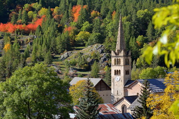 Close-up on the bell tower of Saint Marcellin church in Nevache, Hautes Alpes, France, a traditional village located in Vallee de la Claree (Claree Valley), surrounded by Autumn colors