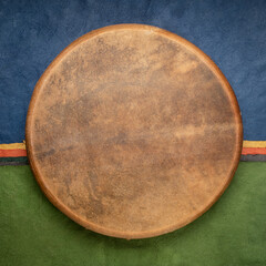 handmade, native American style, shaman frame drum covered by goat skin against colorful abstract...