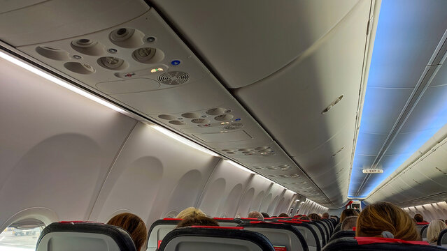 Sitzreihen im Flugzeug mit Fenstern und lichtblauer Beleuchtung