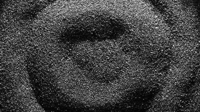Black sand moving. Close-up of a black sand surface moving.