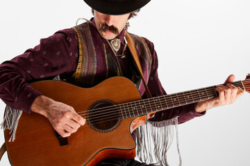 Portrait of man with moustaches in country style clothes playing guitar isolated over white...