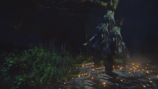 Shaman in black clothes dancing in forest at night surrounded by mysterious lights. Realtime