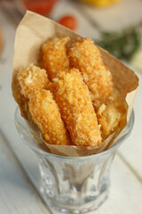 Pile of tasty cheese sticks in a paper and glass