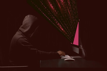 Pirate devant son ordinateur vole des données informatiques - Ambiance rouge