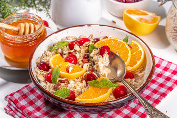 Christmas morning breakfast recipe, cranberry orange oatmeal. Cooked oats porridge with fruit and berry, on white table top view copy space
