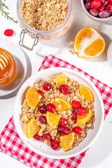 Christmas winter granola with fresh cranberry and orange, with honey and yogurt or milk, on white table background copy space