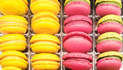 Stack of three yellow lemon macaron with lemon in background
