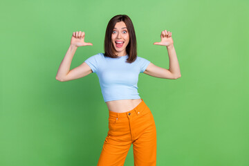 Portrait of positive astonished person direct thumb fingers herself open mouth isolated on green...