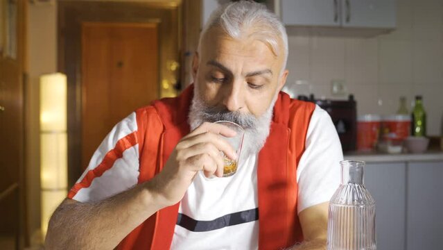 Unhappy man drinking alcohol and contemplating.
Thoughtful mature man drinking alcohol.
