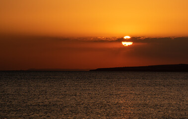 Sunset in the sea with clouds and orange colour. Seascape in the evening. Sun rays in the ocean