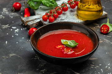 Puree tomato soup with basil on a dark background. Clean eating, dieting, vegan food concept. top view