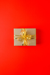 Craft gift box on red background, decorated with a textured bow, creating a romantic luxury atmosphere. For birthday, anniversary presents, gift post cards, banner, flyer, invitation, voucher