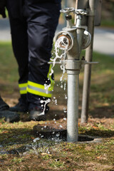 Draining water from a fire hydrant with a firefighter in the background