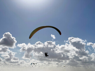 Pilot in paraglider on a beautiful day with some clouds in the sky