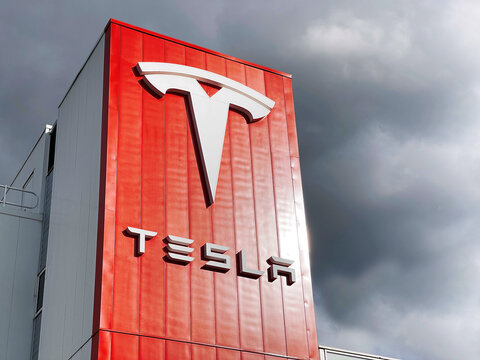 Tesla logo on building of the branch in Amsterdam, Netherlands in front of a dark cloudy sky
