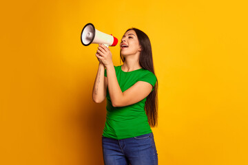 Portrait of young charming girl, student with megaphone isolated on color background. Concept of beauty, art, fashion, human emotions and facial expressions