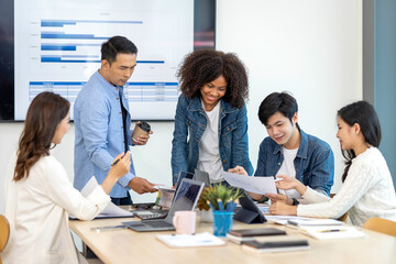 A happy Afro-American and multi-ethnic business men and women working together online on laptops in company offices.