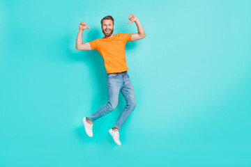 Fototapeta na wymiar Full size photo of optimistic satisfied man muscular beard wear orange t-shirt jeans flying directing at himself isolated on teal color background
