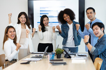 business team celebrates corporate victory together in the office, happy overjoyed professionals group rejoices company victory, teamwork success win triumph concept at the conference table