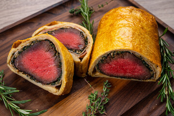 Beef Wellington meat baked in dough on a wooden board.