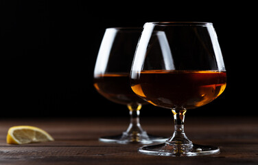 Two glasses of cognac are on a wooden table