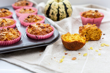 Homemade pumpkin muffins with pumpkin seeds and walnut pieces. Fall baking for Thanksgiving and Halloween. Cupcakes in baking dish on linen napkin. Selective focus. Close up.