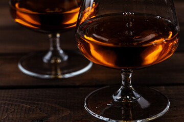 Two glasses of cognac are on a wooden table