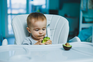 Little adorable baby eating avocado. Vitamin and healthy food for small children. Portrait of...