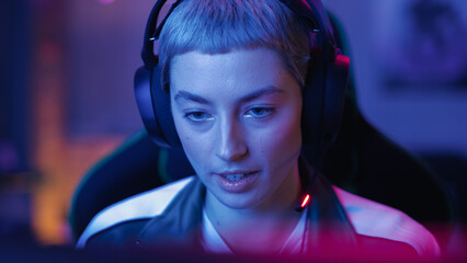 Successful Female Gamer Winning in Online Video Game on Computer. Close Up Portrait of Young Stylish Woman in Headphones Playing PvP Tournament with Other Players, Talking with Team on Microphone.