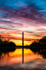 Fiery colorful sunrise over the Washington Monument with reflections in the reflecting pool by the Lincoln Memorial in Washington D.C.