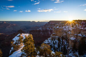 Winter sunrise at Grand Canyon Arizona with snow on the cliffs and the sun peaking above the canyon...