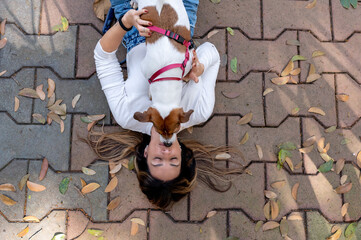 Woman and Jack Russell dog lying on the floor, dry leaves on a warm sunny day