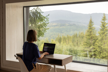 Woman works on laptop remotely in house on nature