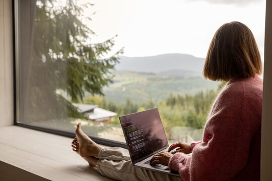 Woman works on laptop at house in mountains