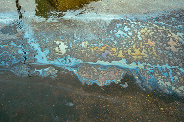 Colorful oil spill on wet pavement. Oil Petrol Rainbow Leak Running Down a Drain