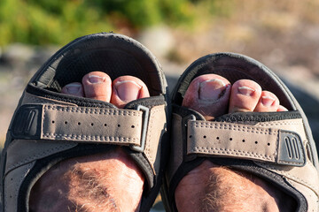 Two dirty feet after a long hike in sandals. Dirty toes sticking up from a pair of sandals. The...