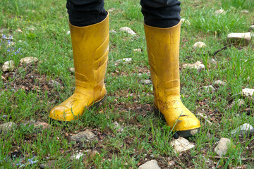 Feet in yellow boots on grass in rainy weather.