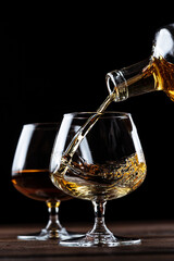 Cognac is poured into a glass from a bottle.