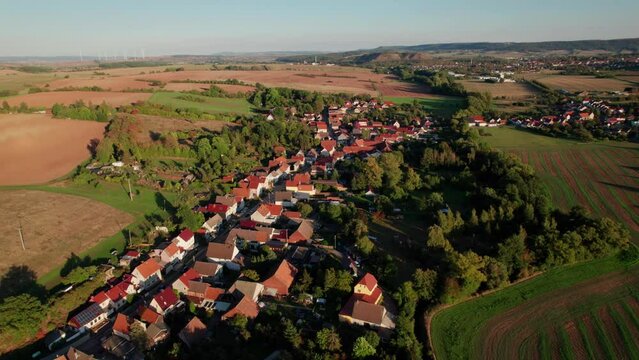 Aer ial view of a German village surrounded by meadows, farmland and forest in Germany.