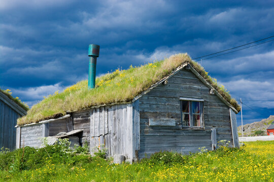 View of wooden peat roof abandoned cottage in Hamningberg against dark stormy sky, Varanger, Norway