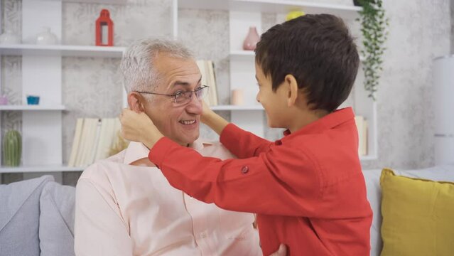 Portrait of happy father and son.
Father and son chatting at home and son playing pranks on his father and having fun.
