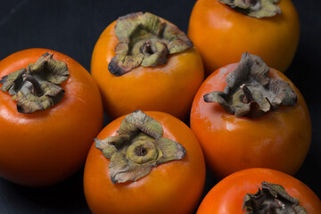 Persimmon on a black background. Ripe and tasty fruit