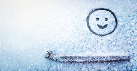 Banner of smiling face (symbol) painted on snow above windshield wiper of car. Winter, transport...