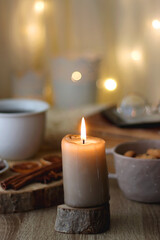 Fototapeta na wymiar Bowl of cookies, cup of tea or coffee, chocolate, spices, knitted blanket, books, glasses and candle on the table. Cozy hygge atmosphere at home. Selective focus.